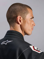 Kombinezon Alpinestars Kart Indoor V2, czarny, zbliżenie na ergonomiczny kołnierz i konstrukcję ramion inspirowaną Formułą 1, białe logo Alpinestars, detale inspirowane wyścigami, wytrzymała tkanina o splocie skośnym