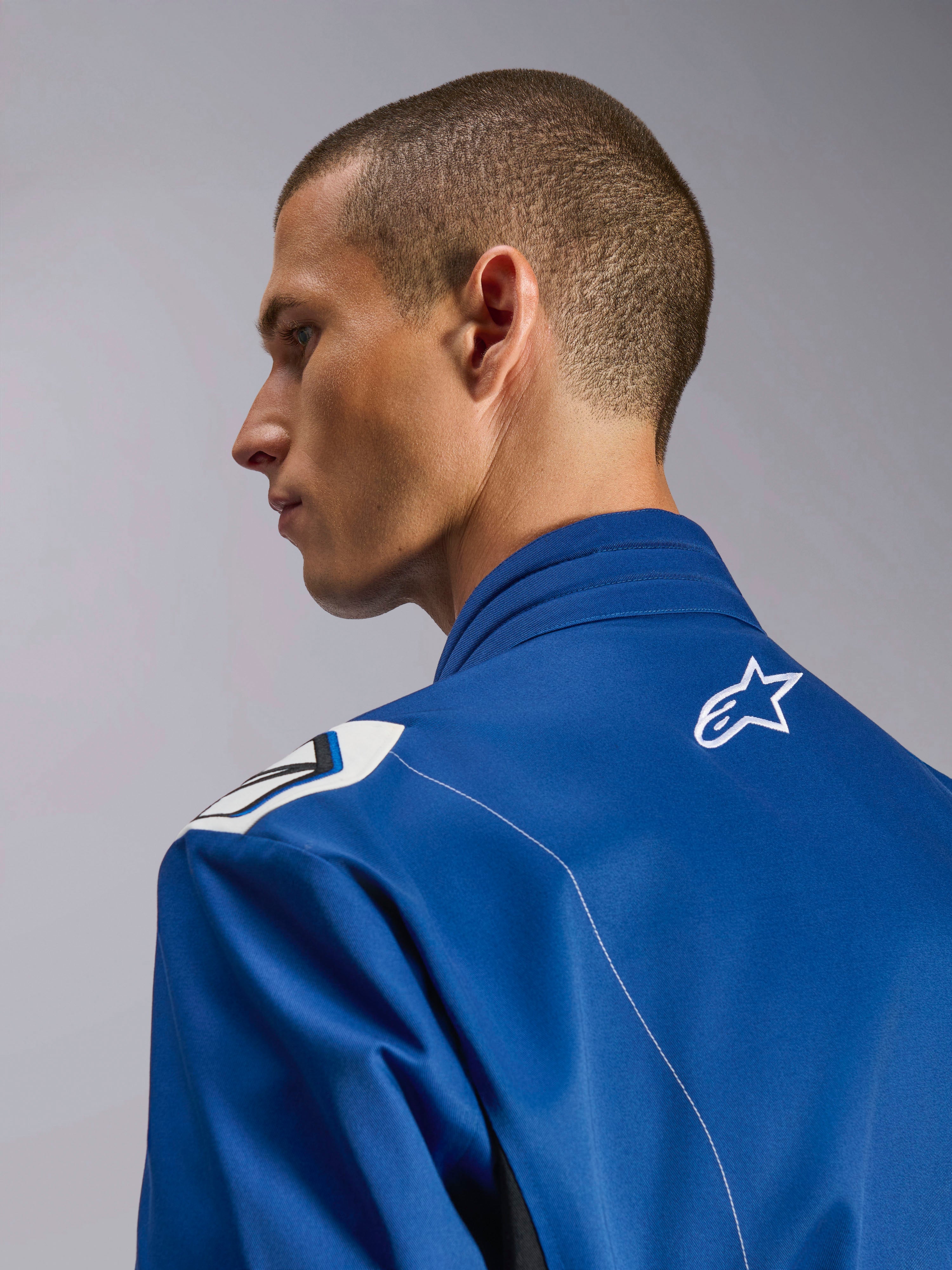 Alpinestars Kart Indoor V2 Suit, niebieski kombinezon kartingowy, zbliżenie z profilu na ergonomiczny kołnierz i górną część pleców z białym logo gwiazdy, ramiona inspirowane Formułą 1, trwała konstrukcja z kepru polibawełnianego
