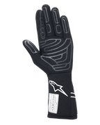 Alpinestars Tech-1 Start V4 Gloves FIA, czarne samochodowe rękawice wyścigowe, widok od strony dłoni z szarymi silikonowymi wzorami chwytnymi, białe logo na przedłużonym mankiecie, etykieta z certyfikatem FIA, profesjonalny sprzęt do sportów motorowych