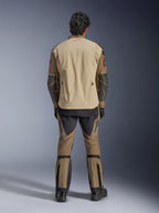 Kurtka Alpinestars Nazca 3L GORE-TEX PRO w kolorze Walnut Rock Brown, widok z tyłu na motocyklistę, widoczne wzmocnienia Superfabric na łokciach i tylne zamki wentylacyjne, noszona z dopasowanymi spodniami adventure, czarnymi butami i rękawicami, wytrzymała techniczna odzież motocyklowa na ekstremalne przygody.
