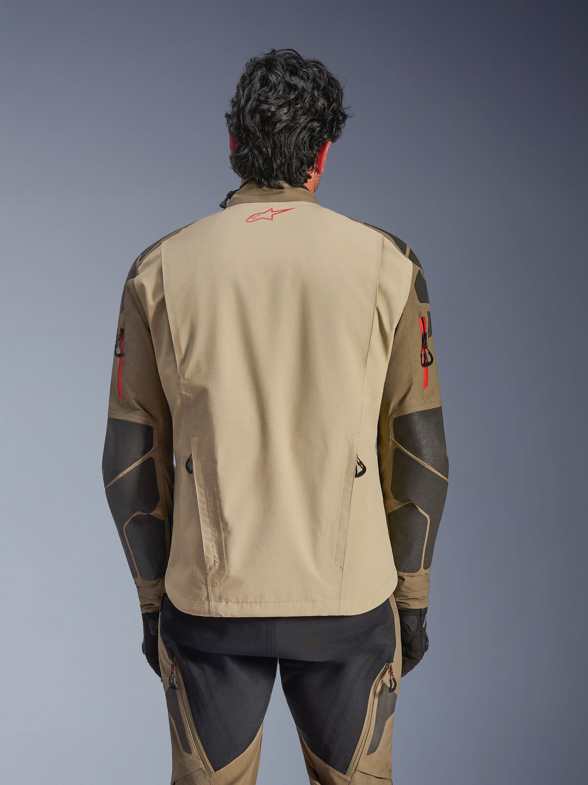 Kurtka Alpinestars Nazca 3L GORE-TEX PRO, widok z tyłu, kolor Walnut Rock Brown, motocyklowa kurtka adventure z czerwonym logo Astars na karku i czerwonymi akcentami zamków na ramionach, ze wzmocnieniami Superfabric na łokciach.
