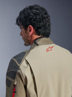 Kurtka Alpinestars Nazca 3L GORE-TEX PRO, kurtka przygodowa w kolorze Walnut Rock Brown, zbliżenie na plecy i ramię, czerwone logo gwiazdy na karku, szare teksturowane panele wzmacniające, wytrzymała konstrukcja tekstylna do jazdy motocyklem