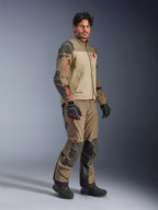 Kurtka Alpinestars Nazca 3L GORE-TEX PRO, Walnut Rock Brown, motocyklowa kurtka przygodowa noszona z pasującymi spodniami i czarnymi rękawicami, z ciemnoszarymi wzmocnieniami, czerwonymi detalami zamków i wysokowydajną laminowaną powłoką.