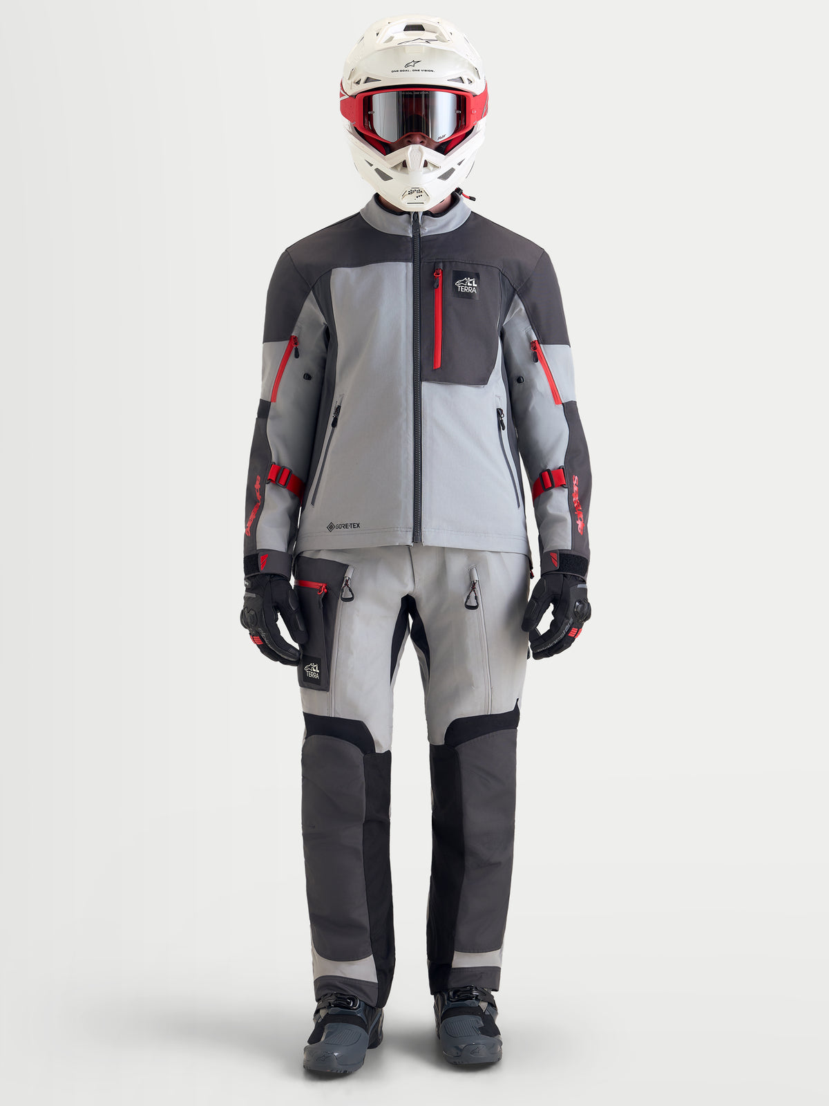 Alpinestars Arenis Gore-Tex kurtka motocyklowa męska adventure, w kolorze średnioszarym, ciemnoszarym i czarnym, na modelu w pełnym ekwipunku turystycznym z kaskiem i pasującymi spodniami