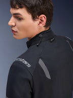 Kurtka Alpinestars ST-7 2L GORE-TEX, czarno-ciemnoszara kurtka motocyklowa, zbliżenie na kołnierz pokazujące regulację ściągaczem i etykietę Tech-Air, szare odblaskowe akcenty oraz logo marki na ramieniu