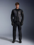 Męski model ubrany w kurtkę Alpinestars ST-7 2L GORE-TEX w kolorze Deep Gray Black Dark Khaki, z brandingiem „ALPINESTARS EXPLORATION EQUIPMENT” na klatce piersiowej, w połączeniu z pasującymi czarnymi spodniami motocyklowymi, rękawicami i butami, ujęcie studyjne od przodu.