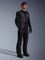 Męski model w kurtce Alpinestars ST-7 2L GORE-TEX w kolorach Deep Gray Black i Dark Khaki, zestaw z czarnymi spodniami i rękawicami adventure, wodoodporna laminowana powłoka z kieszeniami cargo i technicznym brandingiem, idealna do turystyki przygodowej