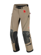 Alpinestars Nazca 3L GORE-TEX PRO Pants, motocyklowe spodnie adventure, orzechowe i czarne, z czerwoną naszywką z logo All Terra, oznaczeniem GORE-TEX PRO, czarnymi wzmocnieniami Superfabric na kolanach i goleniach, wentylacją na udach zapinaną na zamek oraz zintegrowanym paskiem z klamrą magnetyczną.