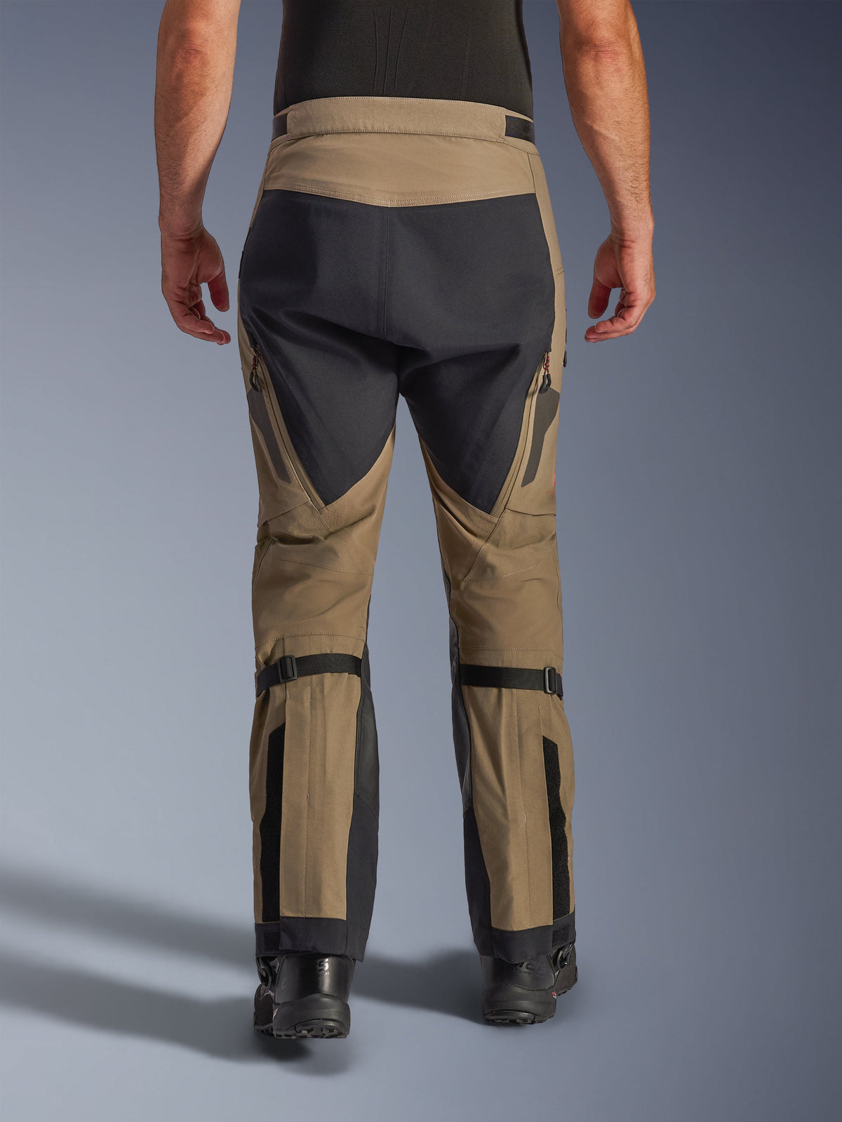 Spodnie Alpinestars Nazca 3L GORE-TEX PRO, orzechowe i czarne, widok z tyłu przedstawiający regulatory objętości łydek i wzmocnione panele, techniczne motocyklowe spodnie adventure na każdą pogodę
