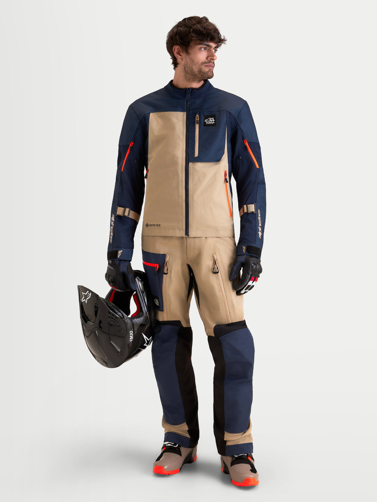 Alpinestars Arenis Gore Tex Spodnie, męskie spodnie motocyklowe adventure w kolorze granatowym i beżowym, na model prezentujący pasujący sprzęt ADV z kaskiem