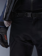 Spodnie Alpinestars ST-7 2L GORE-TEX, czarne, zbliżenie na pas z magnetycznym zapięciem na klamrę i wytrzymałą techniczną konstrukcją tekstylną, noszone z pasującą kurtką adventure touring i czarnymi rękawicami z czerwonym logo.