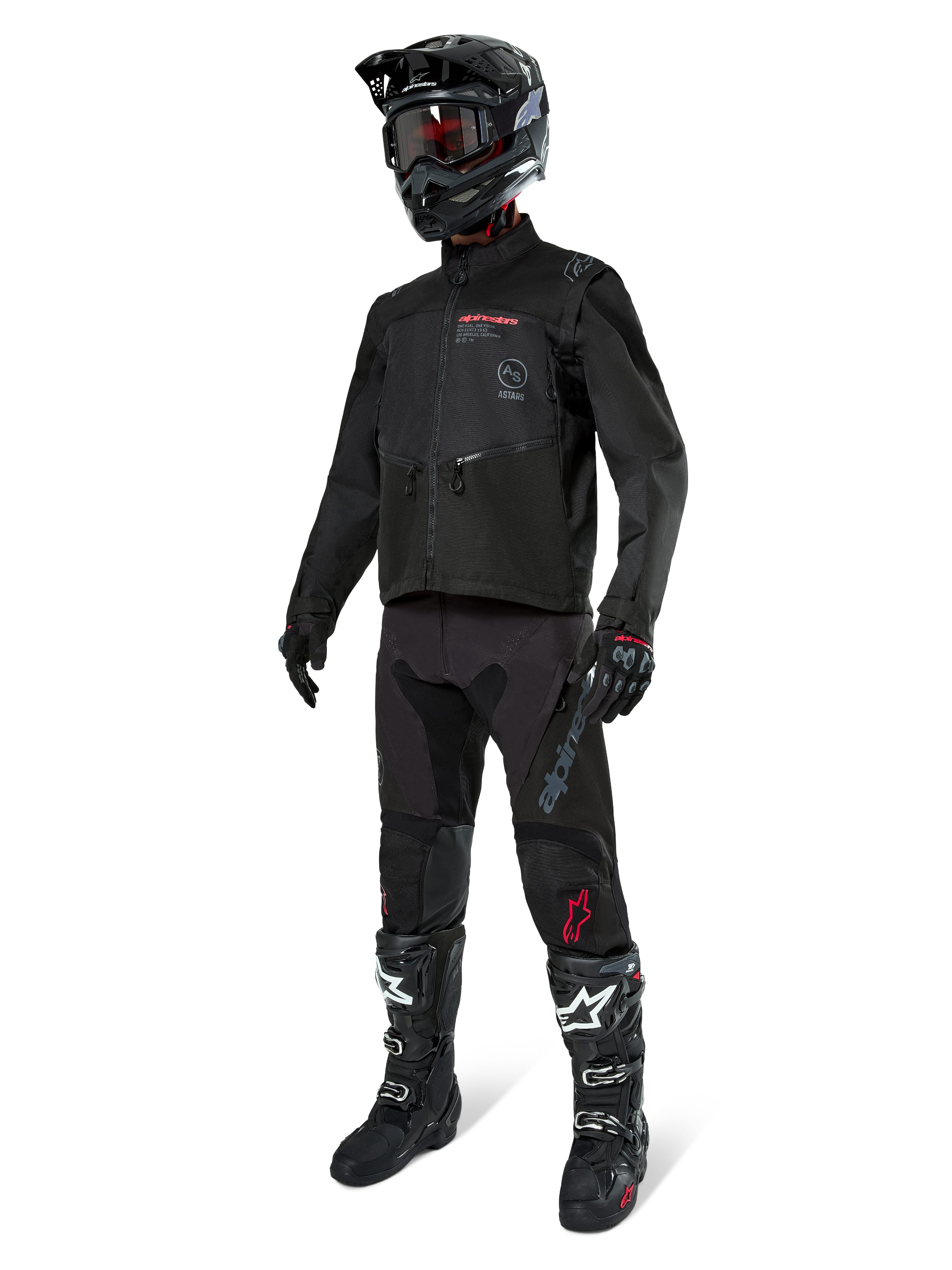 Motocyklista motocrossowy w pełnym stroju wyścigowym, kurtka Alpinestars Pro-Dura w kolorze czarnym, czarne spodnie z szarym brandingiem i czerwonymi akcentami, czarny kask z goglami oraz czarno-białe buty motocrossowe, dopasowany ubiór do jazdy enduro i off-road