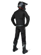 Alpinestars Pro-Dura Jacket, czarna kurtka off-road enduro, widok z tyłu w zestawie z pasującymi spodniami i czarnymi butami Tech 10, wyraźne logo Alpinestars na dole pleców, wytrzymała konstrukcja tekstylna do agresywnej jazdy po szlakach