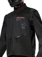Kurtka Alpinestars Pro-Dura, czarna motocyklowa kurtka off-road z czerwonym brandingiem Alpinestars i szarym okrągłym logo Astars na piersi, kieszenie na ręce zapinane na zamek, trwała konstrukcja z materiału ripstop, design inspirowany rajdami do jazdy enduro