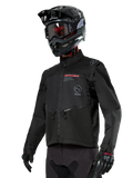 Alpinestars Pro-Dura Jacket, motocyklowa kurtka off-road, czarna z czerwonymi i szarymi elementami graficznymi, posiada przednie kieszenie na zamek i wysoki kołnierz, zestawiona z czarnym kaskiem motocrossowym i rękawicami do jazdy enduro