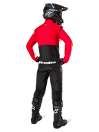 Motocross rider from behind wearing Alpinestars Lite-Dura Softshell Jacket, Black Bright Red and White, featuring a red upper panel and black lower section with white branding, paired with black pants, black helmet, and black boots, coordinated enduro outfit for off-road riding