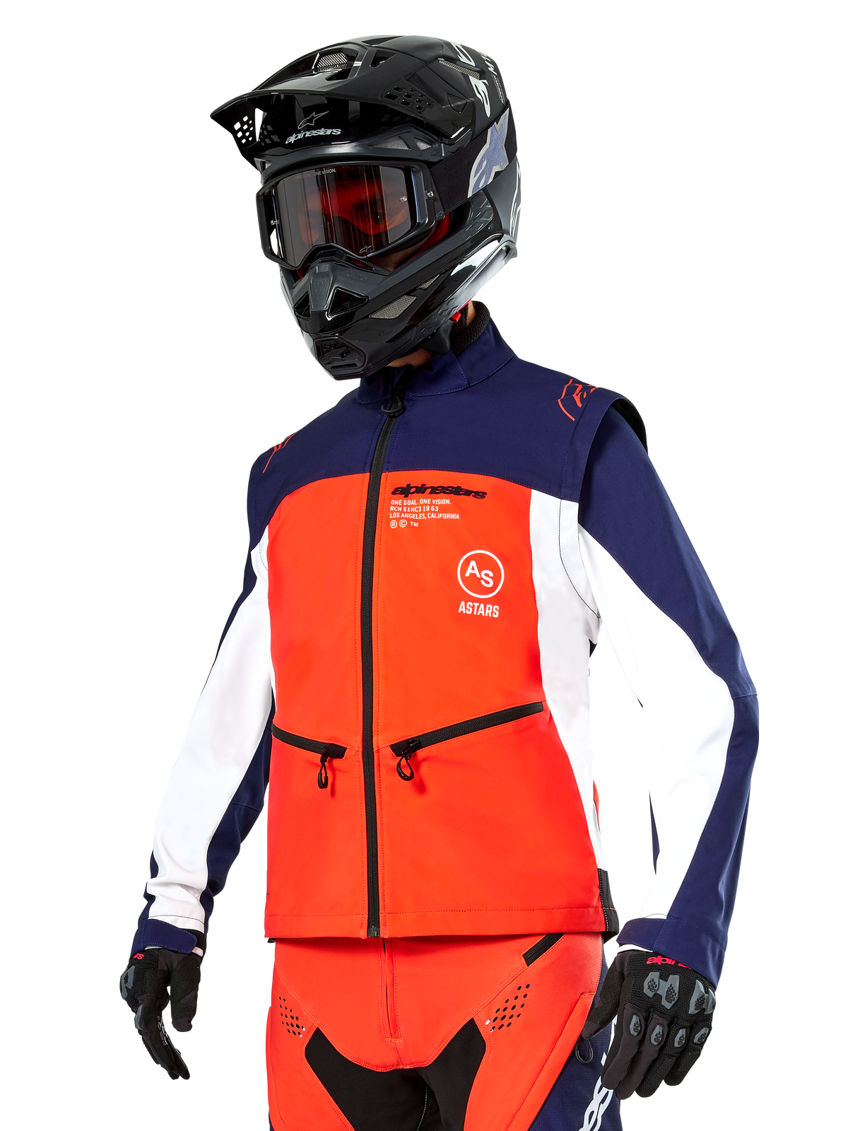 Kurtka Alpinestars Lite-Dura Softshell w kolorach granatowym, jaskrawym pomarańczowym i białym, odzież motocrossowa, noszona z czarnym kaskiem i goglami, rękawicami ochronnymi oraz pasującymi spodniami wyścigowymi