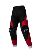 Alpinestars 2025 Kids Racer Veil Pants, młodzieżowe spodnie motocrossowe, czarne i jaskrawoczerwone, białe logo na udach i kolanach, białe mankiety przy kostkach, wstępnie zakrzywiona ergonomiczna konstrukcja, wytrzymały materiał do jazdy terenowej
