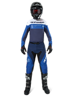 Spodnie Alpinestars Pro-Dura, spodnie motocrossowe i enduro, granatowe, jasnoniebieskie i białe, zawodnik w pełnym zestawie wyścigowym z pasującą koszulką, czarnym kaskiem, czerwonymi goglami i czarnymi butami, profesjonalny zestaw odzieży off-road