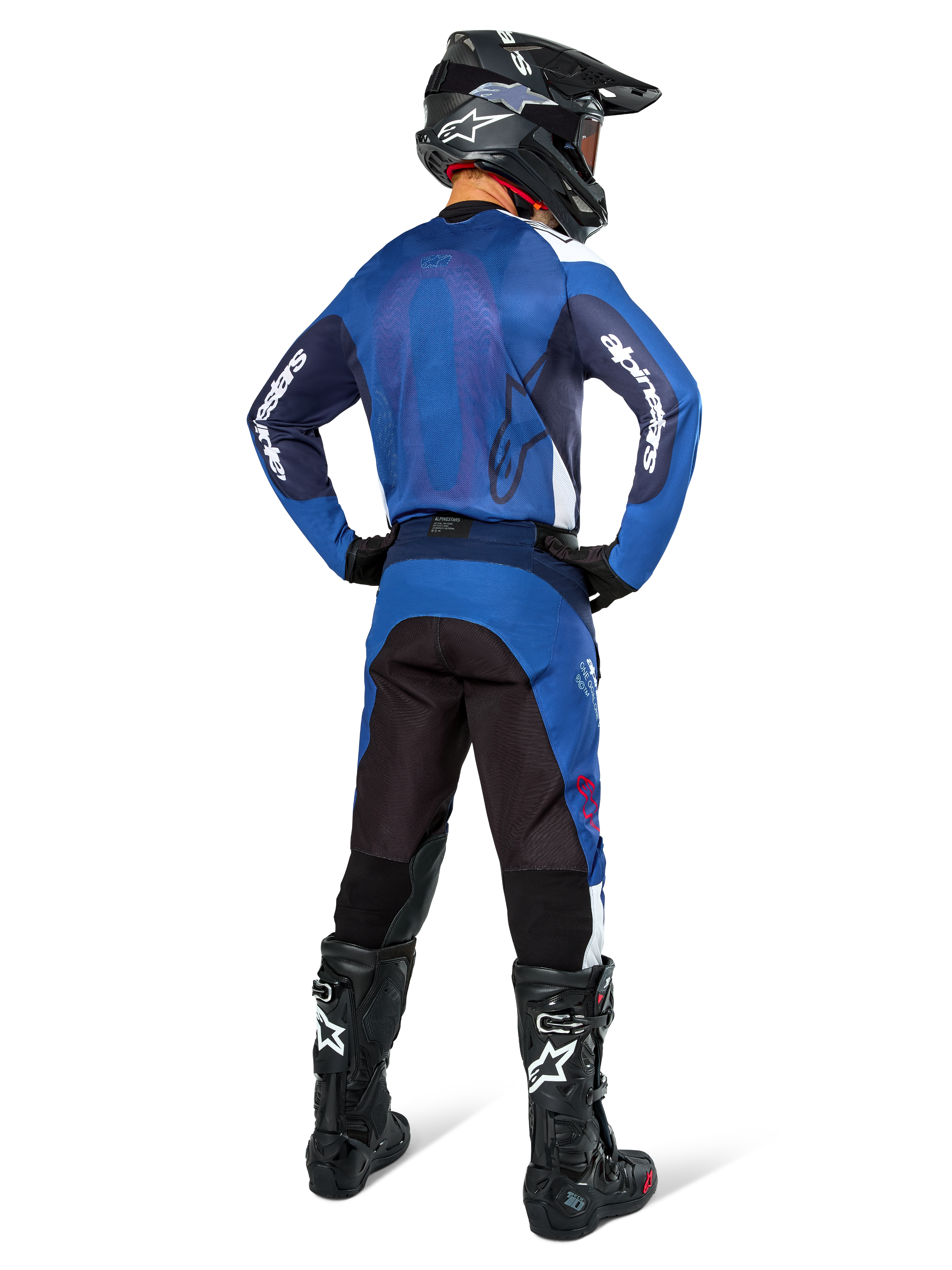 Spodnie Alpinestars Pro-Dura, spodnie do motocrossu i enduro, granatowe, jasnoniebieskie i białe, widok z tyłu, noszone z pasującą niebieską bluzą, czarnym kaskiem i czarnymi butami Tech, wytrzymała konstrukcja z elastycznymi wstawkami do jazdy w terenie