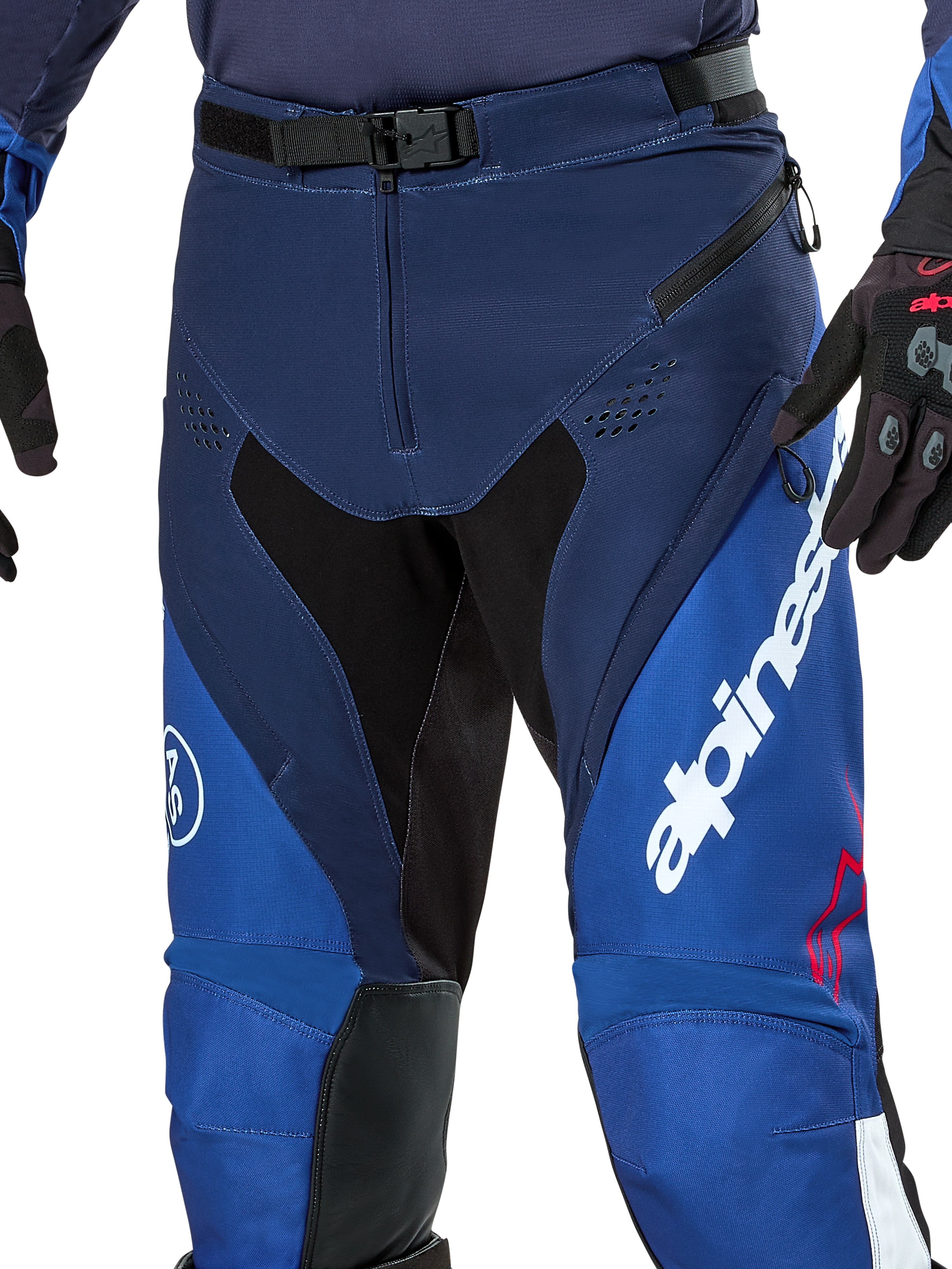 Alpinestars Pro-Dura Pants, spodnie do enduro i motocrossu, granatowe, jasnoniebieskie i białe, widok z bliska na magnetyczne zapięcie SX2 w pasie, zapinane na zamek otwory wentylacyjne na udach oraz wytrzymałe, elastyczne panele z wyraźnym białym brandingiem.