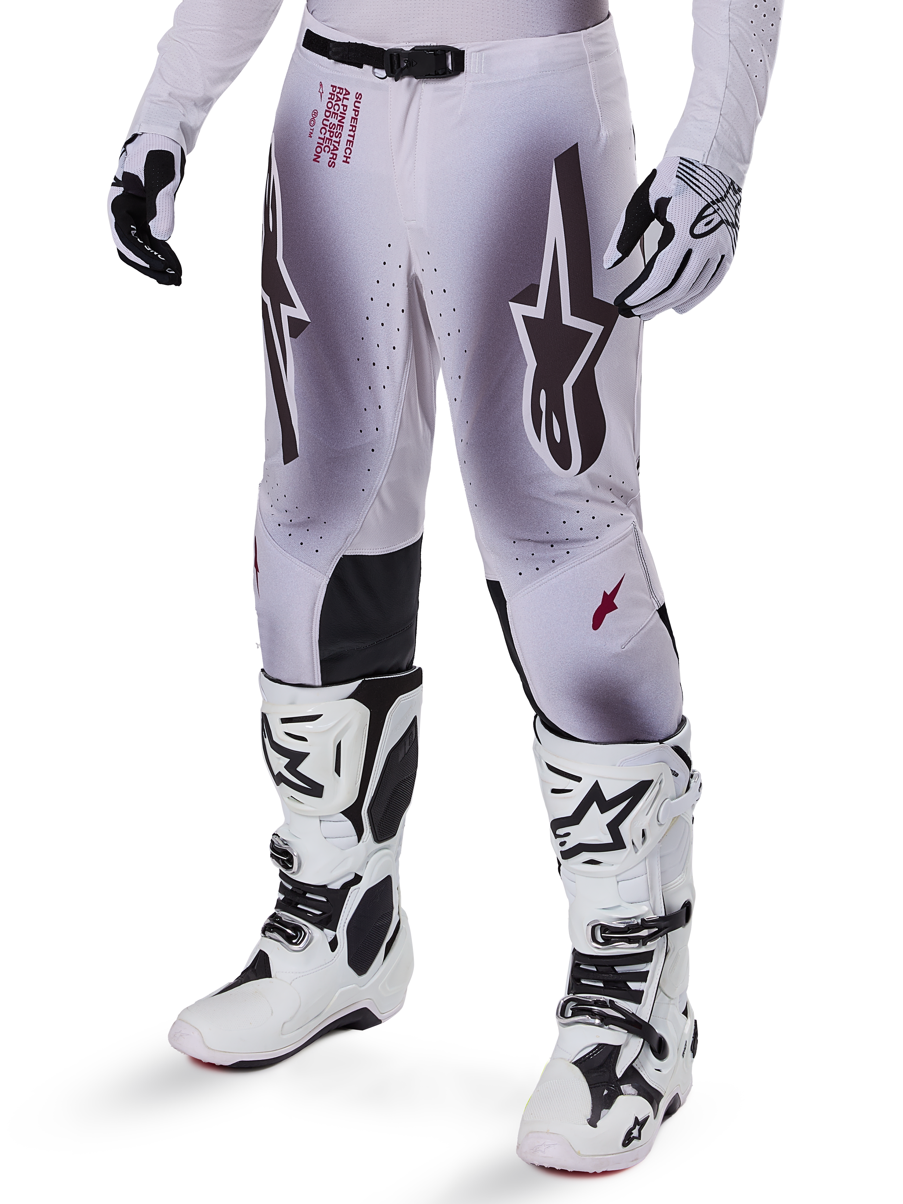 Alpinestars Supertech Maker Pants 2025, spodnie motocrossowe, srebrno-czarne, z dużym logo gwiazdy i czerwonymi napisami, prezentowane z dopasowanymi białymi butami i rękawicami
