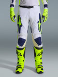 Alpinestars 2026 Racer Air Riway Pants, spodnie motocrossowe, jasnoszare, neonowożółte i niebieskie, noszone z pasującymi neonowożółtymi rękawicami i butami, z perforowanymi przednimi panelami zapewniającymi przepływ powietrza, wyraziste niebieskie i żółte logo, sportowy design do jazdy terenowej