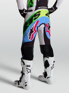 Alpinestars Spodnie Supertech Dyna, męskie spodnie motocrossowe, fioletowe, zielone i czarne, perforowana konstrukcja z kozią skórą na kolanach, pokazane od tyłu w butach Tech 10