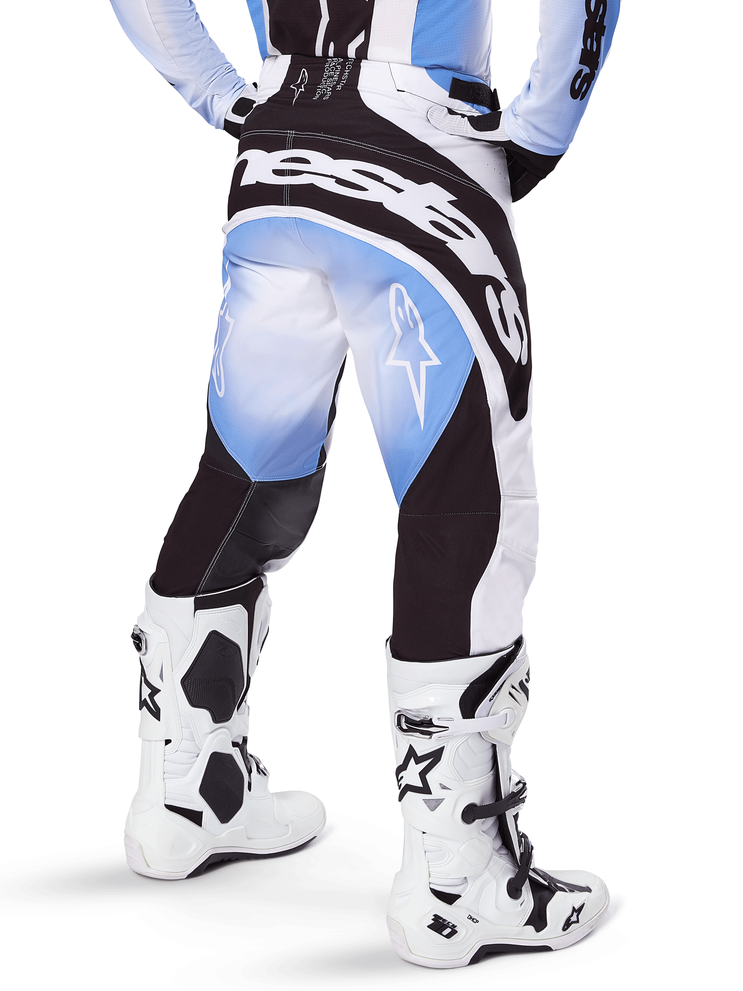 Alpinestars Techstar Melt Pants 2025, spodnie motocrossowe, czarno-niebiesko-białe, widok z tyłu z wyraźnym napisem Alpinestars na siedzeniu i logo gwiazdy na nogawkach, biało-czarne buty Tech 10, profesjonalna odzież off-road