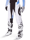 Spodnie Alpinestars Techstar Melt 2025, spodnie motocrossowe, białe i czarne z niebieskimi akcentami, laserowo wycinane perforacje dla przepływu powietrza i konstrukcja kolan Babel, noszone z dopasowanymi białymi butami i rękawicami motocrossowymi, sportowy design do wyścigów terenowych