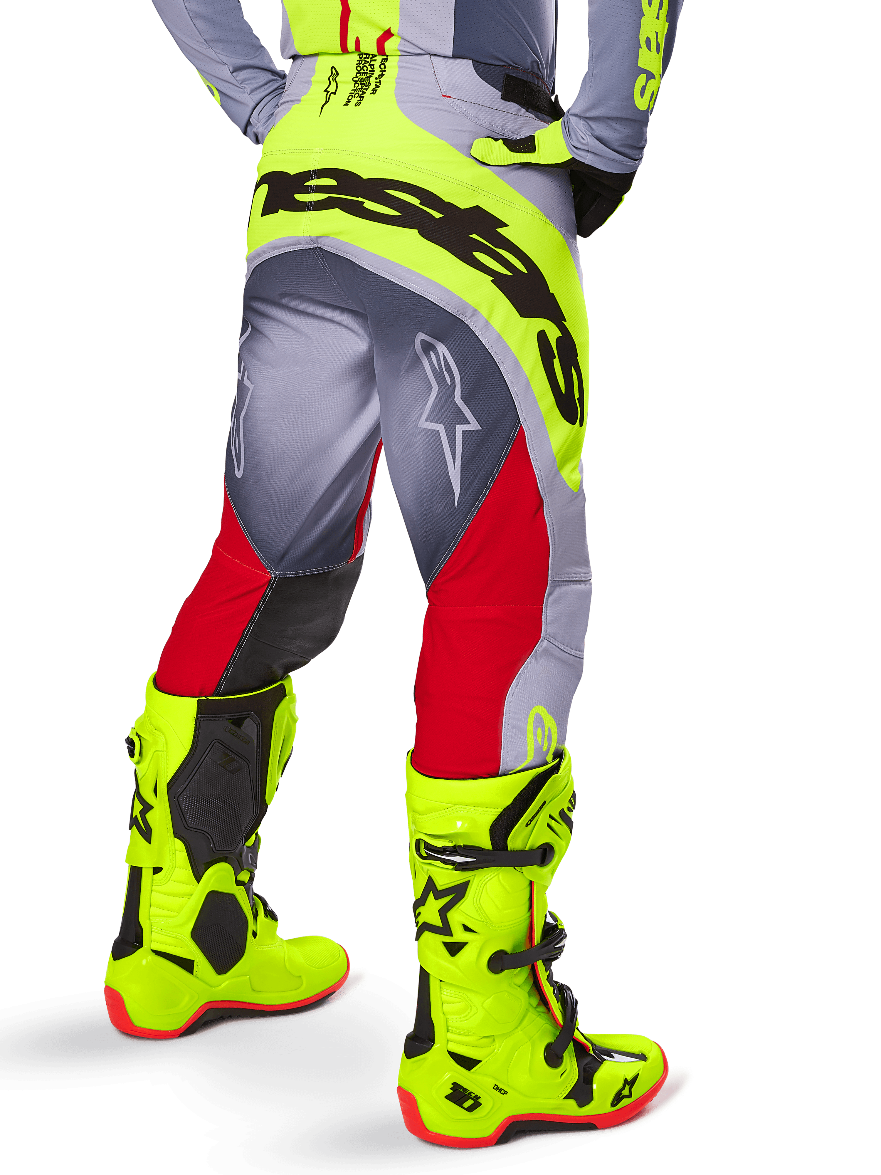 Alpinestars Techstar Melt Pants 2025, spodnie motocrossowe, jaskrawoczerwone i szare z neonowożółtymi akcentami, widok z tyłu eksponujący duże czarne logo na siedzeniu, noszone z pasującymi jaskrawożółtymi butami i szarą koszulką, sportowy krój wyścigowy do zawodów off-road