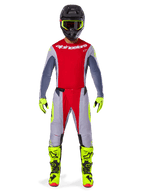 Motocrosszysta w zestawie Alpinestars 2025 Techstar Melt w kolorystyce Bright Red Gray, czerwona koszulka z szarymi rękawami, szare spodnie z czerwonymi i neonowożółtymi akcentami, dopasowane neonowożółte buty i rękawice, czarny kask z neonowożółtymi goglami.