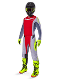 Motocyklista motocrossowy w zestawie Alpinestars 2025 Techstar Melt, czerwono-szara bluza i spodnie, jaskrawożółte neonowe rękawice i buty, czarny kask, kompletny zestaw wyścigowy off-road
