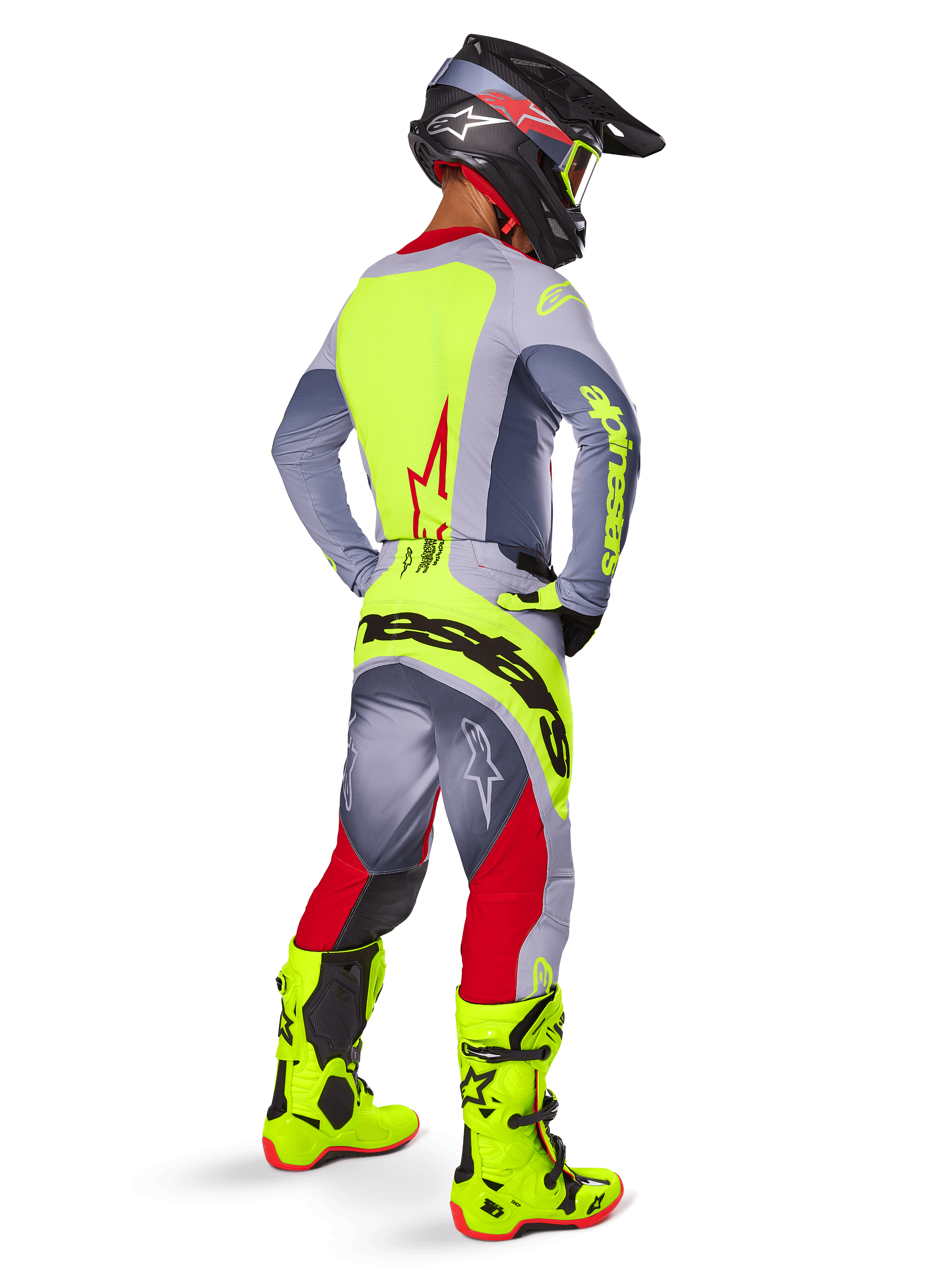 Zawodnik motocrossowy w zestawie Alpinestars 2025 Techstar Melt Gear Set, widok z tyłu, szara koszulka z neonowożółtym panelem na plecach i czerwonym logo gwiazdy, szaro-czerwone spodnie z wyraźnym neonowożółtym napisem 'Alpinestars' na siedzeniu, jaskrawe neonowożółte buty motocrossowe i pasujący kask