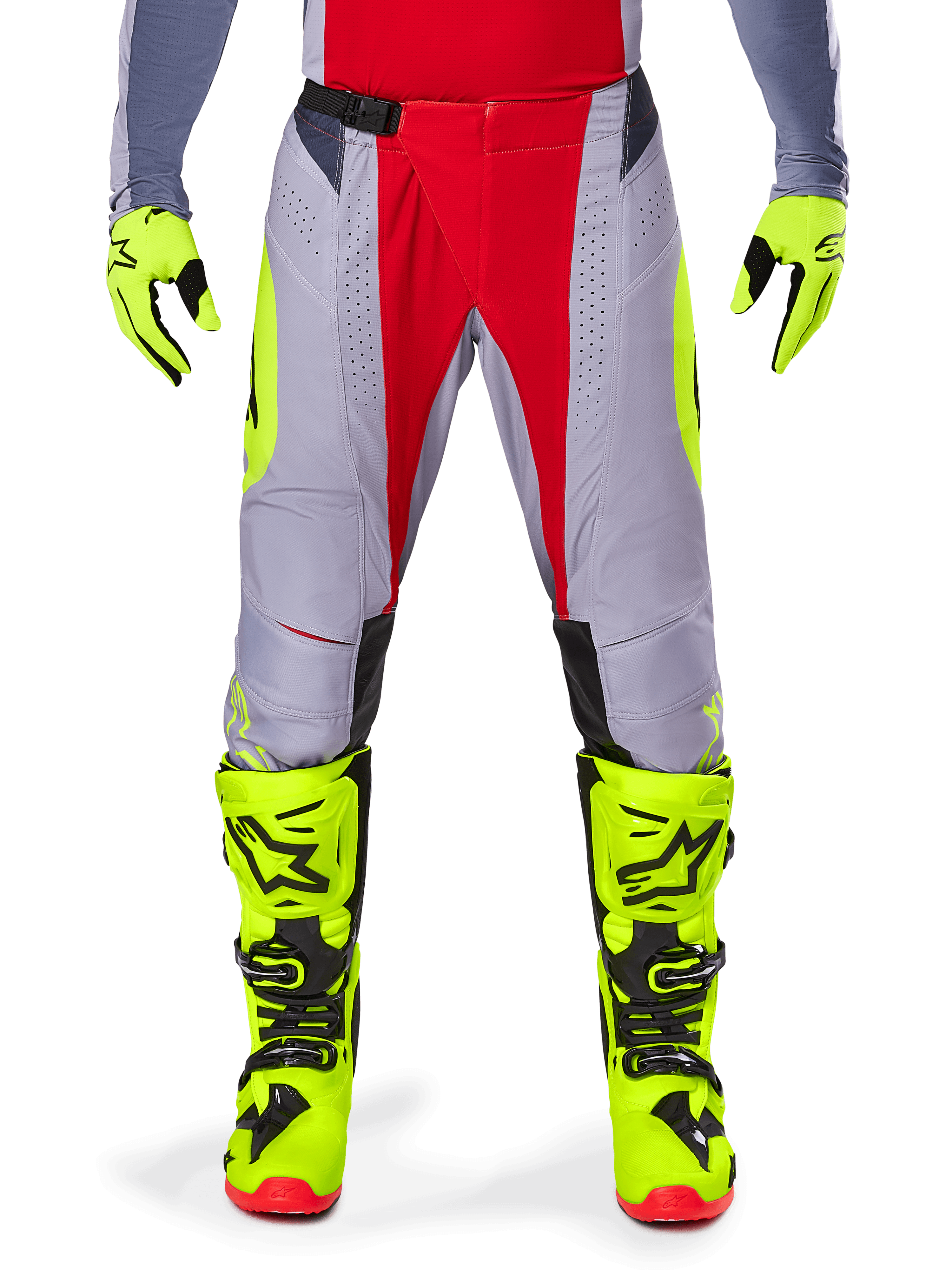Spodnie Alpinestars Techstar Melt 2025, spodnie motocrossowe, jaskrawoczerwone i szare z fluorescencyjnymi żółtymi akcentami, noszone z dopasowanymi neonowożółtymi rękawicami i butami, z magnetyczną klamrą w pasie i laserowo wycinanymi perforacjami zapewniającymi wentylację.