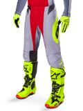 Alpinestars Techstar Melt Pants 2025, spodnie motocrossowe, jasnoczerwone i szare z neonowożółtymi grafikami bocznymi i czarnymi panelami na kolanach, w zestawieniu z pasującymi neonowożółtymi butami i rękawicami, zaprojektowane do wyczynowej jazdy terenowej