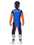 Zawodnik motocrossowy w kompletnym stroju wyścigowym, zestaw Alpinestars 2025 Techstar Melt, niebiesko-pomarańczowy, niebieska koszulka z pomarańczowymi rękawami, pasujące spodnie z białym logo, czarny kask z niebieskimi goglami, biało-czarne buty i rękawice, skoordynowany strój do wyścigów off-road