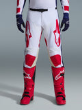 Spodnie Alpinestars Racer Riway 2026, spodnie motocrossowe, biało-niebiesko-czerwone, zestawione z czerwonymi butami i granatowymi rękawicami, duże czerwone logo na udach i czerwone panele na kolanach, sportowy, profilowany krój z regulowaną klamrą w pasie