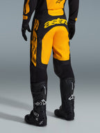 Alpinestars Racer Riway Pants 2026, spodnie motocrossowe, żółto-czarne, widok z tyłu ukazujący wyraźne żółte logo astars na siedzeniu i nogawce, w zestawieniu z czarnymi butami i rękawicami motocrossowymi