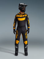 Spodnie Alpinestars Racer Riway 2026, spodnie motocrossowe, żółto-czarne, noszone jako kompletny zestaw wyścigowy z dopasowaną koszulką z długim rękawem, czarnym kaskiem, czarnymi goglami i czarnymi butami z białym logo gwiazdy, profesjonalna odzież off-road