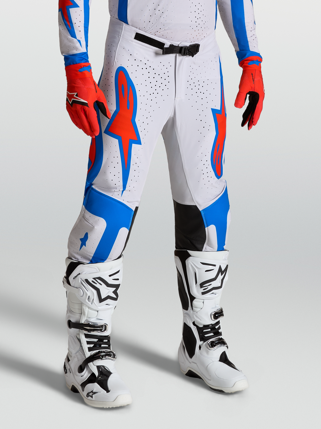 Spodnie Supertech Vesta, białe i czerwone spodnie motocrossowe z niebieską grafiką gwiazd, sportowy krój wyścigowy off-road.