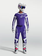 Spodnie Alpinestars Supertech Vesta, męskie spodnie motocrossowe, niebieskie i białe, sportowy krój z wytrzymałej tkaniny rip-stop, widok na modelu w pełnym stroju wyścigowym.