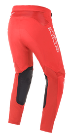 Spodnie Alpinestars Supertech Blaze, spodnie motocrossowe, jasnoczerwone, widok z tyłu z trzech czwartych, białe logo Alpinestars i czarne skórzane wzmocnienia wewnętrznej części kolan, zaprojektowane do jazdy terenowej