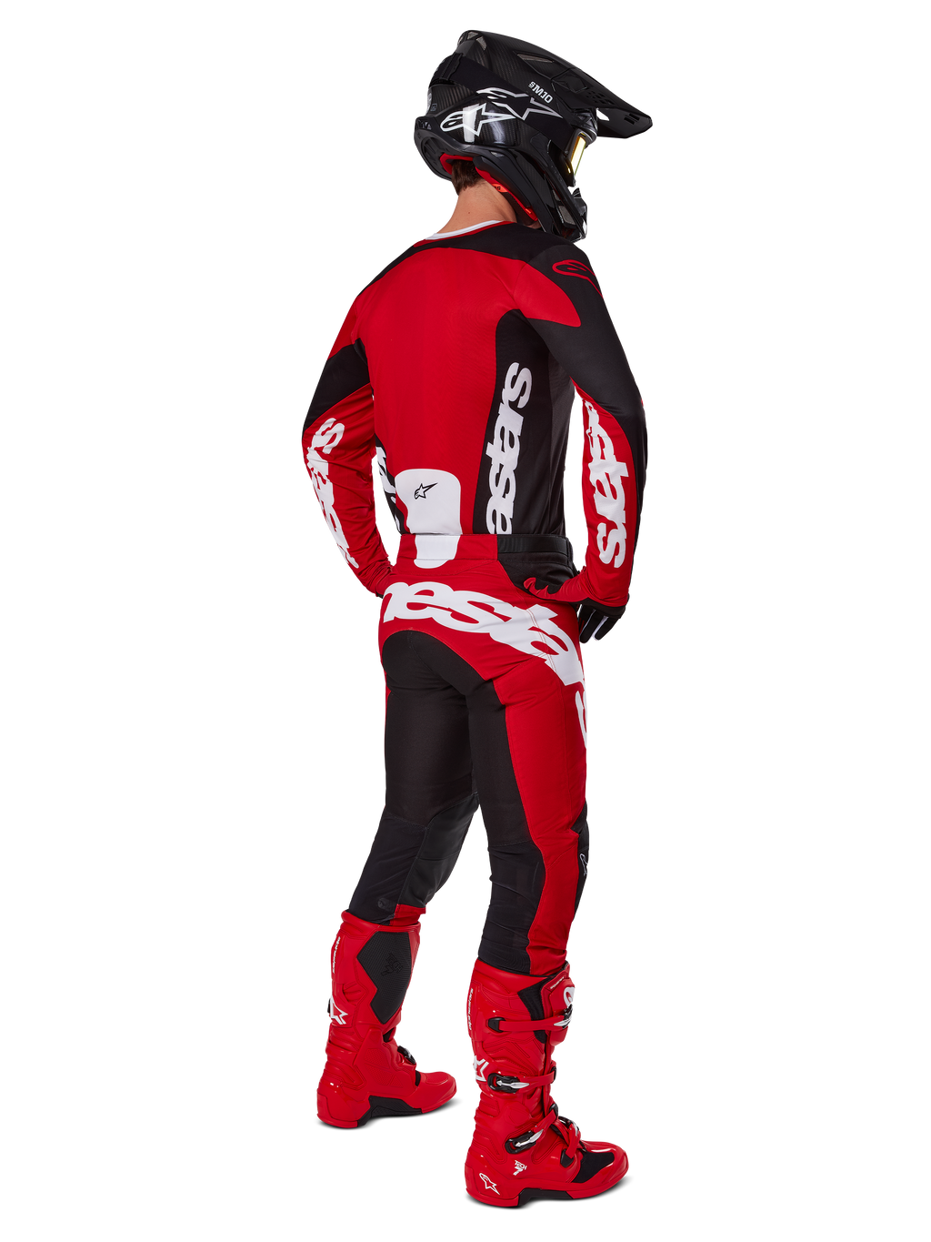 Zestaw Alpinestars 2025 Racer Veil, motocyklista motocrossowy widziany od tyłu w czerwonej koszulce z czarnymi panelami i białym logo, pasujące czerwono-czarne spodnie z dużymi białymi oznaczeniami marki, czerwone buty i czarny kask, kompletny strój wyścigowy off-road