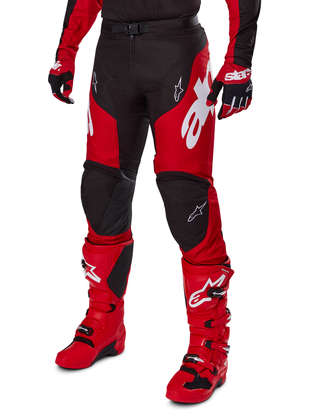 Motocyklista motocrossowy w zestawie Alpinestars 2025 Racer Veil, czerwono-czarna koszulka i spodnie z białym logo, dopasowane rękawice i jaskrawoczerwone buty motocrossowe, profesjonalna odzież do jazdy terenowej.