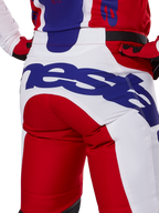 Alpinestars Racer Veil Pants 2025, spodnie motocrossowe, jaskrawoczerwone i białe z niebieskim brandingiem, widok z tyłu na detal siedziska z dużym logo Alpinestars, element dopasowanego stroju wyścigowego off-road