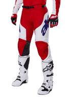 Spodnie Alpinestars Racer Veil 2025, spodnie motocrossowe, intensywnie czerwone i białe, z niebieskimi logo Alpinestars i czarnymi skórzanymi panelami na kolanach, zestawione z czerwonymi rękawicami i białymi butami motocrossowymi, skoordynowany komplet odzieży do wyścigów terenowych