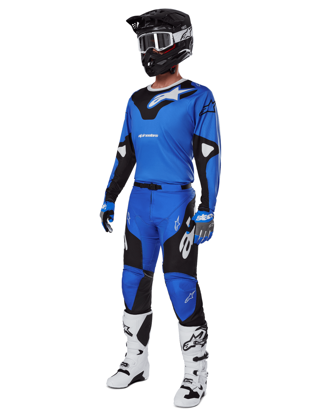 Zawodnik motocrossowy w kompletnym stroju wyścigowym, spodnie Alpinestars 2025 Racer Veil w kolorze niebiesko-czarnym, dopasowana niebieska koszulka z białymi akcentami, czarny kask z białymi goglami, biało-czarne buty i niebieskie rękawice, spójny zestaw do jazdy terenowej