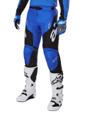 Alpinestars Racer Veil Pants 2025, spodnie motocrossowe, niebiesko-czarne z białymi akcentami graficznymi, noszone z pasującą niebieską koszulką, rękawicami i białymi butami, wytrzymała odzież ochronna do wyścigów terenowych