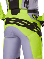 Alpinestars 2025 Racer Veil Pants, spodnie motocrossowe, szare i żółte neonowe, widok z tyłu z dużym czarnym brandingiem na siedzeniu, noszone z pasującą bluzą i rękawicami, techniczny design off-road